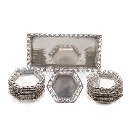 Hallmarked. Rectangular tray with openworked borders and fifteen hexagonal matching plates. 15x8 cms. the tray; 6,5 cms. diam. the plates. 681 gr.